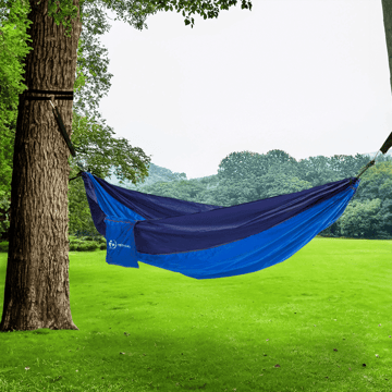 Basecamp hammock between 2 trees in a grassy field.