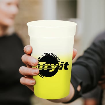 A person holding a branded mood cup at an event.
