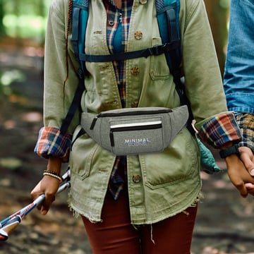 Woman wearing a branded fanny pack while hiking through the woods.