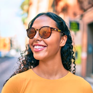 A woman wearing branded sunglasses and smiling.