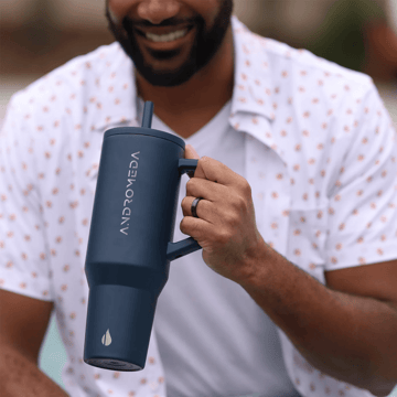 Man holding a large, Stanley-cup style tumbler.