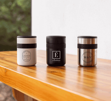 Three can coolers lined up on a wood table.